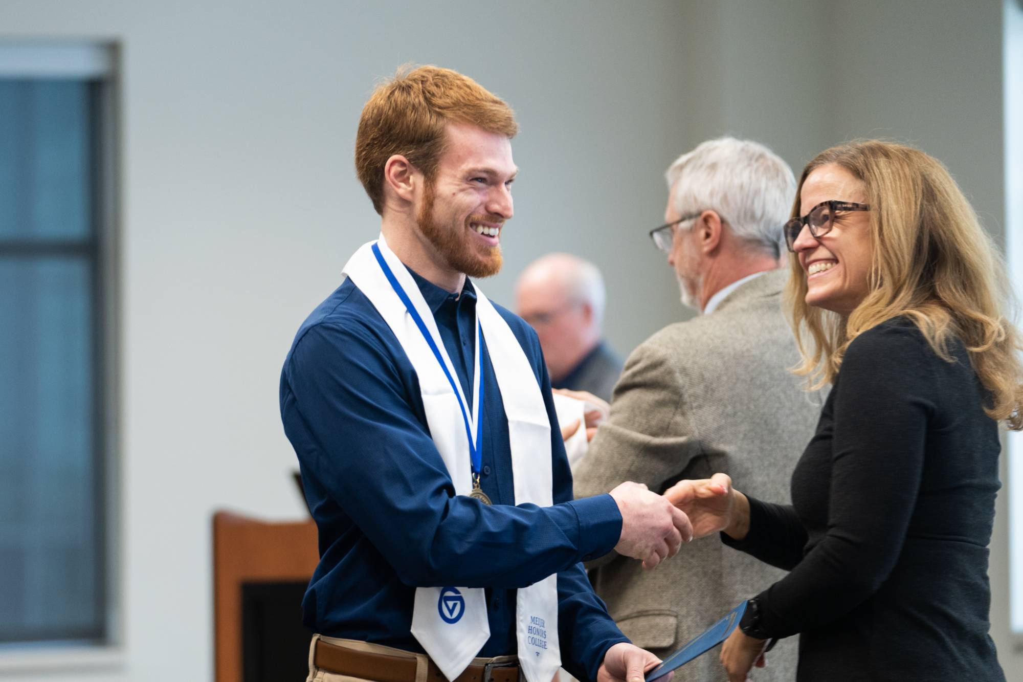 Honors graduate shakes hands with Dr. Ellen Adams.